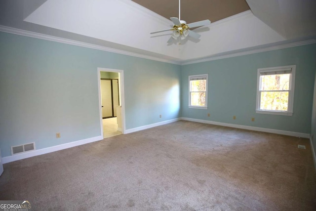 carpeted spare room featuring crown molding, ceiling fan, and a raised ceiling