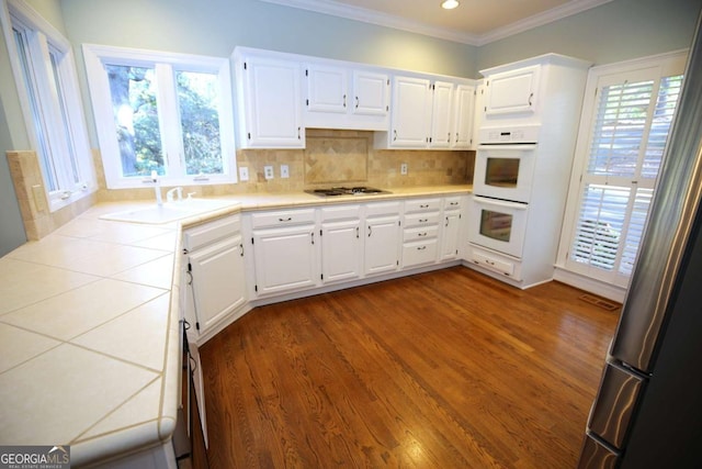 kitchen with sink, gas stovetop, white cabinetry, crown molding, and decorative backsplash