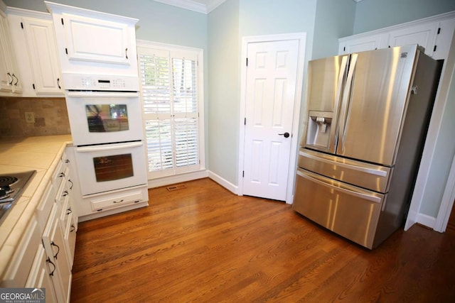 kitchen featuring double oven, white cabinetry, decorative backsplash, stainless steel refrigerator with ice dispenser, and dark wood-type flooring