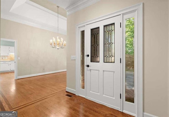 foyer with crown molding, hardwood / wood-style floors, and a chandelier