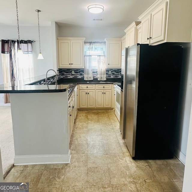 kitchen with stainless steel fridge, hanging light fixtures, backsplash, kitchen peninsula, and cream cabinetry