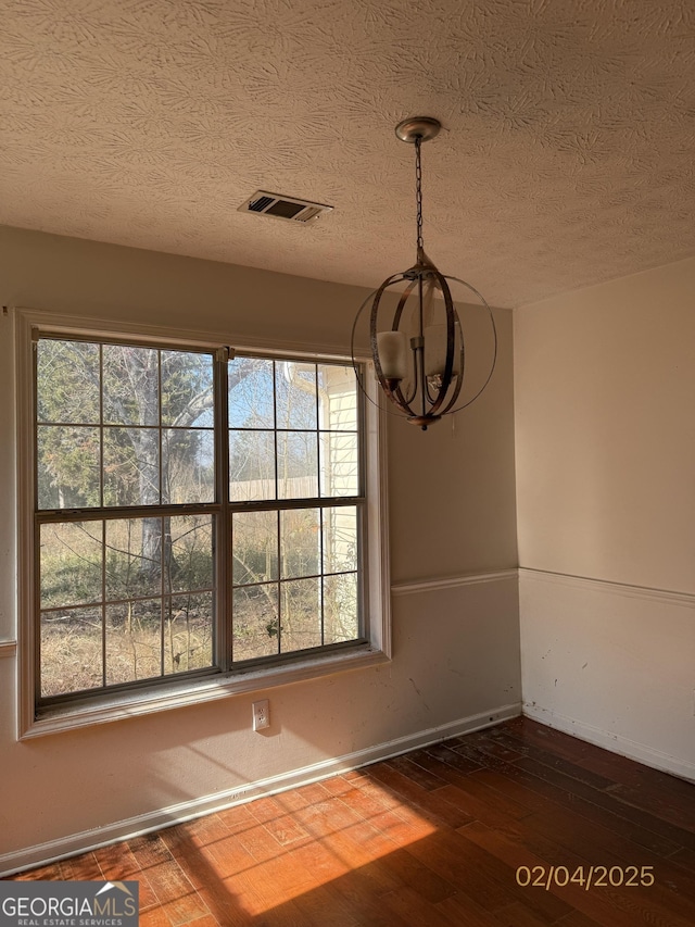 unfurnished dining area with a textured ceiling and dark hardwood / wood-style flooring