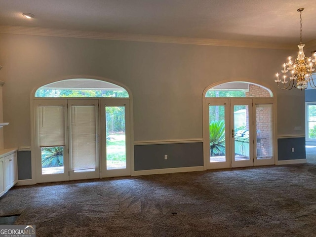 entrance foyer with a notable chandelier, crown molding, a towering ceiling, and dark colored carpet