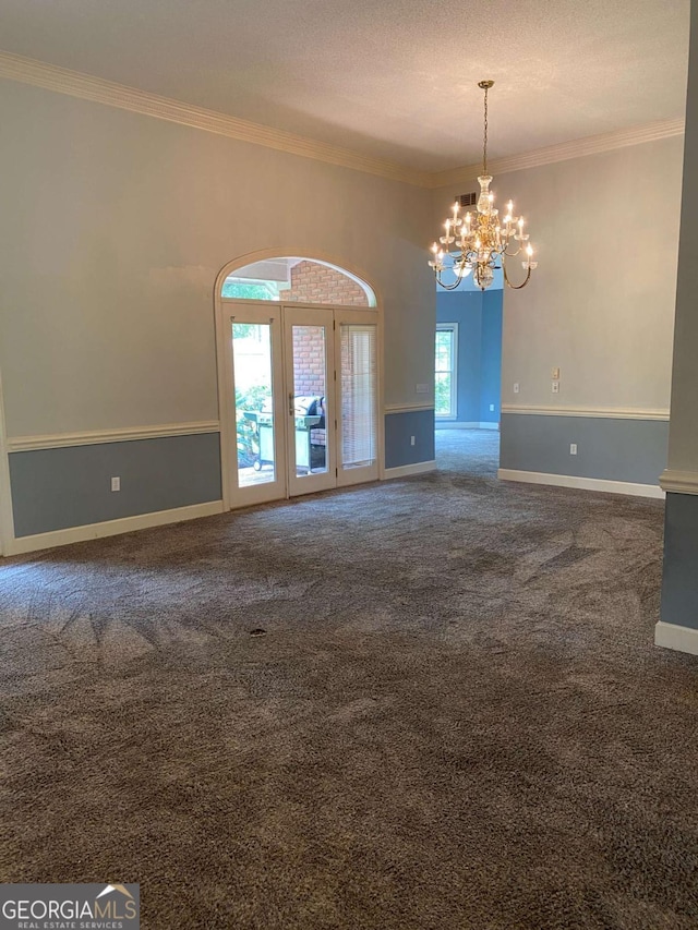 spare room featuring a textured ceiling, ornamental molding, a chandelier, and carpet flooring