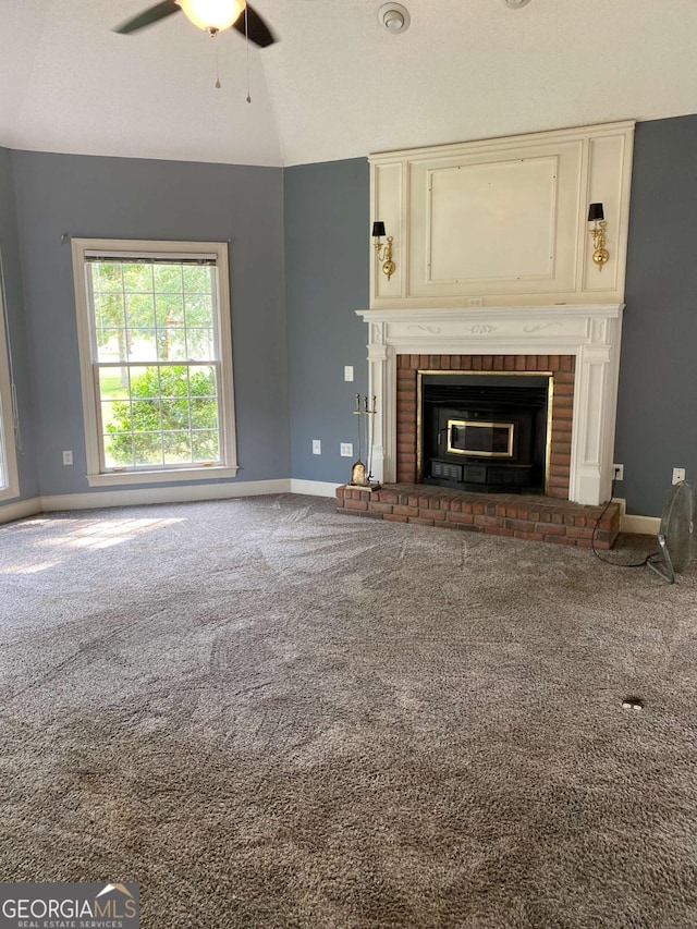 unfurnished living room featuring a brick fireplace, carpet flooring, lofted ceiling, and ceiling fan