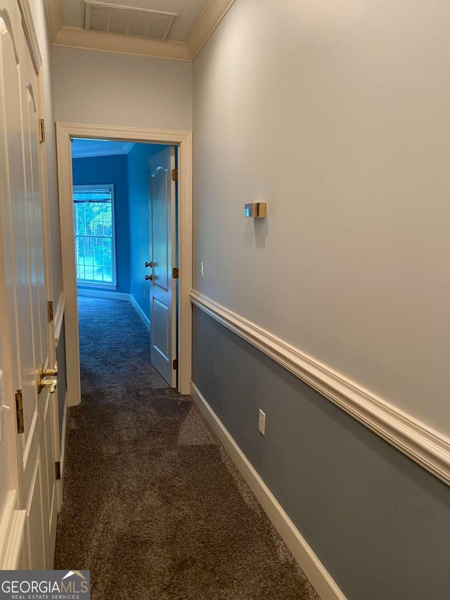 corridor with ornamental molding and dark carpet