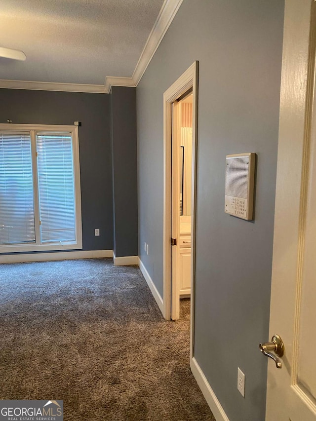 empty room with crown molding, dark carpet, and a textured ceiling