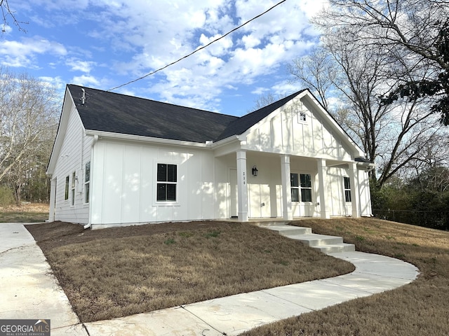 view of front facade with a porch, board and batten siding, and a front lawn