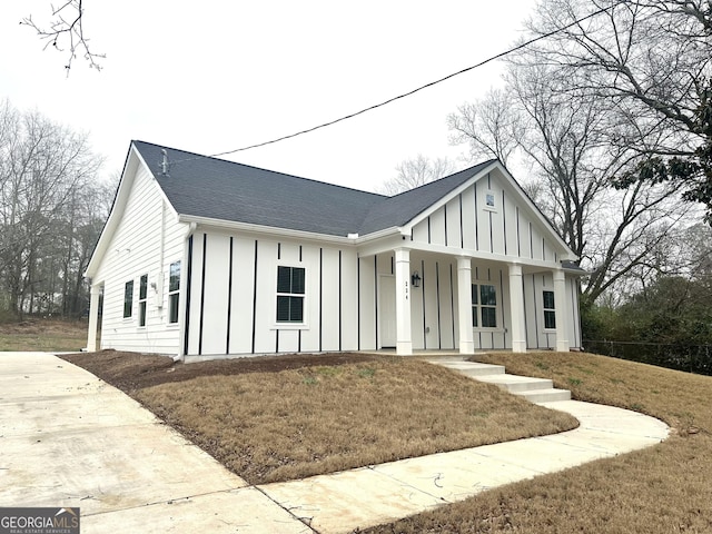 modern inspired farmhouse featuring covered porch and a front lawn