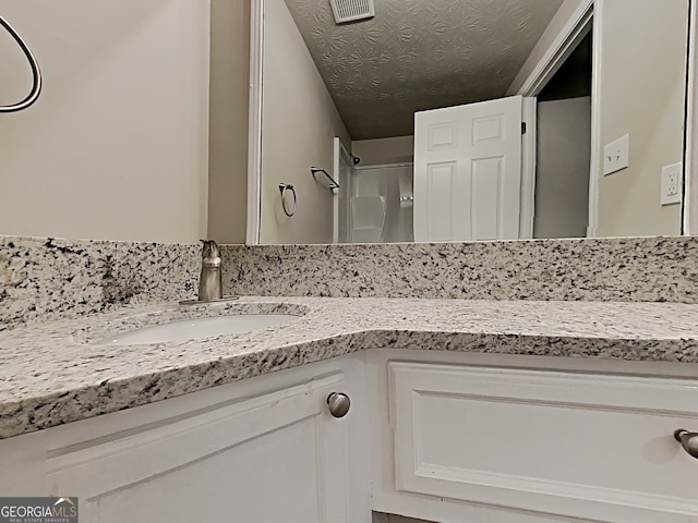 bathroom featuring vanity, a shower, and a textured ceiling