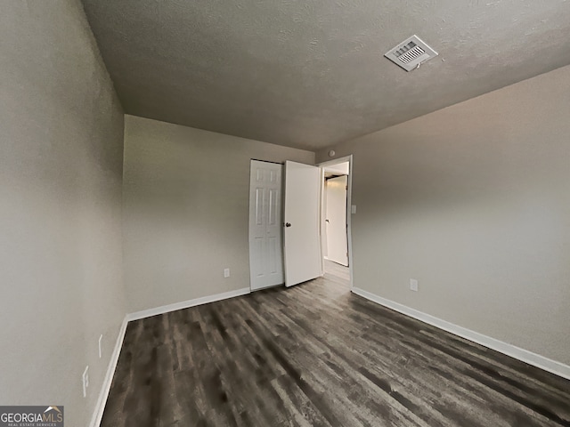 unfurnished room featuring dark hardwood / wood-style flooring and a textured ceiling