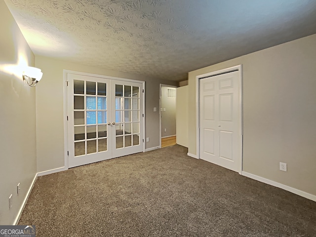 empty room with carpet, a textured ceiling, and french doors