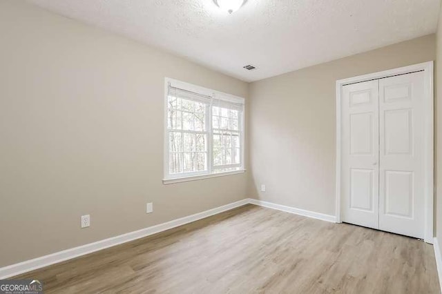 145 Price Hills Ct, Sugar Hill, GA 30518 - unfurnished bedroom with wood finished floors, a closet, and a textured ceiling