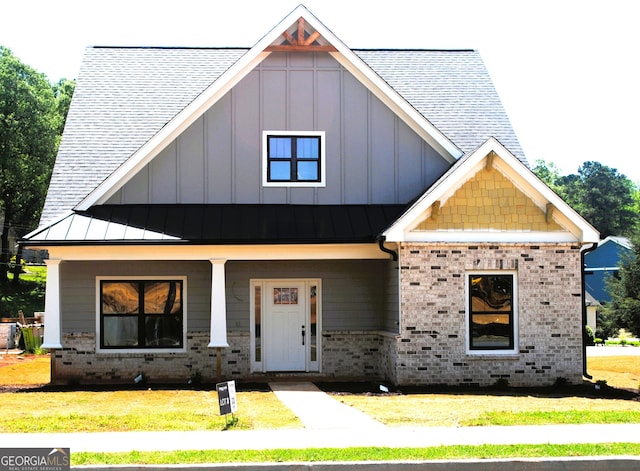 view of front facade featuring board and batten siding, a porch, a front lawn, and brick siding