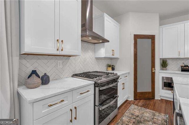 kitchen with dark wood-style floors, backsplash, wall chimney range hood, double oven range, and white cabinetry