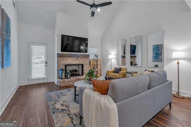 living room featuring high vaulted ceiling, a ceiling fan, wood finished floors, a fireplace, and baseboards