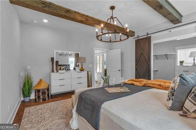 bedroom with beamed ceiling, multiple windows, a chandelier, and a barn door