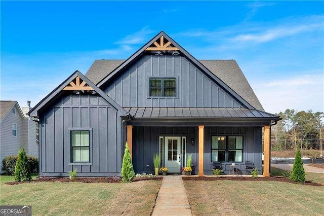 modern farmhouse with a standing seam roof, a porch, metal roof, board and batten siding, and a front yard