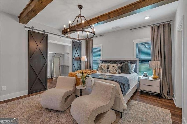 bedroom with beam ceiling, a barn door, an inviting chandelier, multiple windows, and wood finished floors