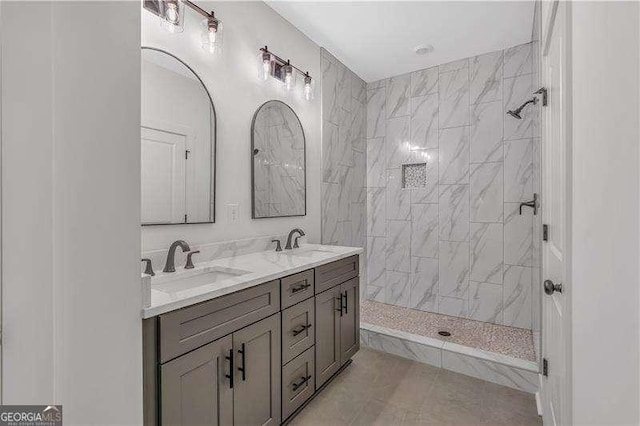 bathroom with double vanity, tile patterned flooring, tiled shower, and a sink