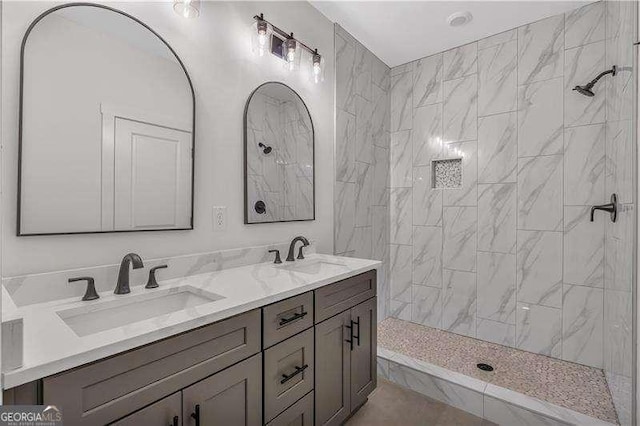 full bathroom with a tile shower, double vanity, and a sink