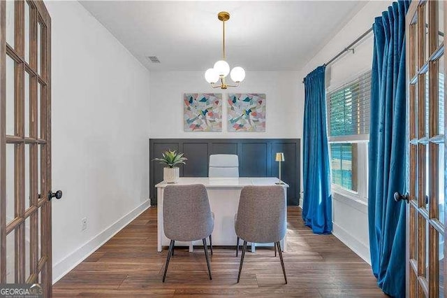 dining room featuring wood finished floors, french doors, and an inviting chandelier