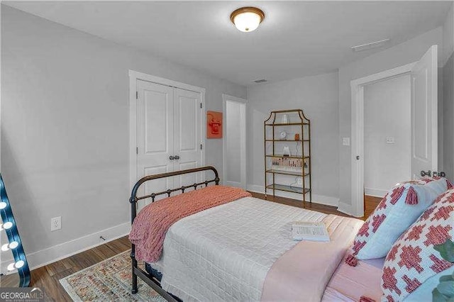 bedroom featuring baseboards, wood finished floors, and a closet