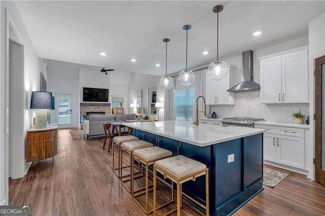 kitchen with dark wood finished floors, tasteful backsplash, white cabinetry, gas stove, and wall chimney range hood