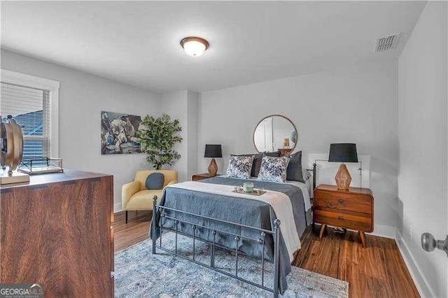 bedroom featuring wood finished floors, visible vents, and baseboards