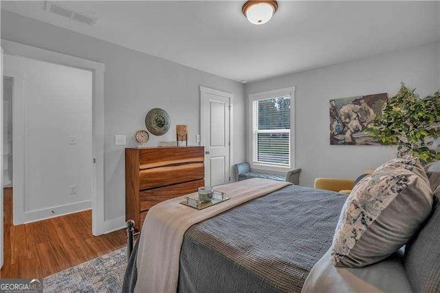bedroom with baseboards, wood finished floors, and visible vents
