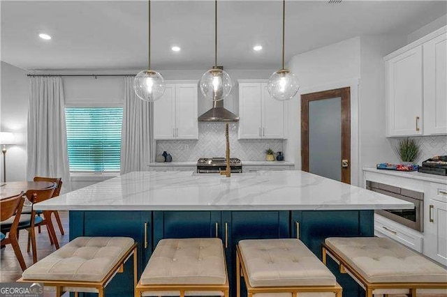 kitchen with light stone counters, tasteful backsplash, white cabinets, wall chimney exhaust hood, and stove