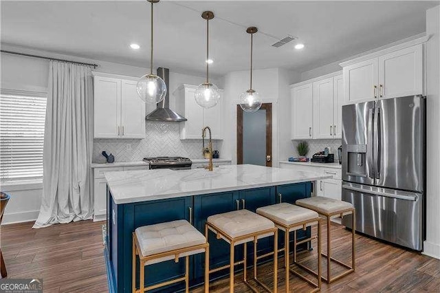kitchen with stove, wall chimney range hood, visible vents, decorative backsplash, and stainless steel refrigerator with ice dispenser
