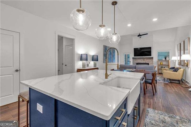 kitchen featuring dark wood-style floors, a ceiling fan, a fireplace, blue cabinetry, and open floor plan