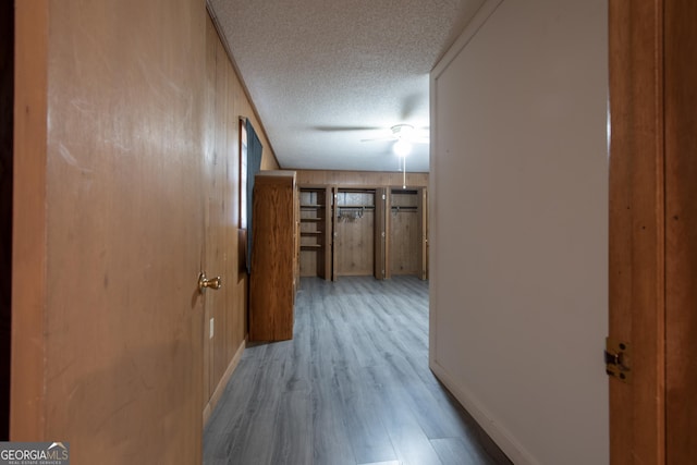 corridor with a textured ceiling and light hardwood / wood-style flooring