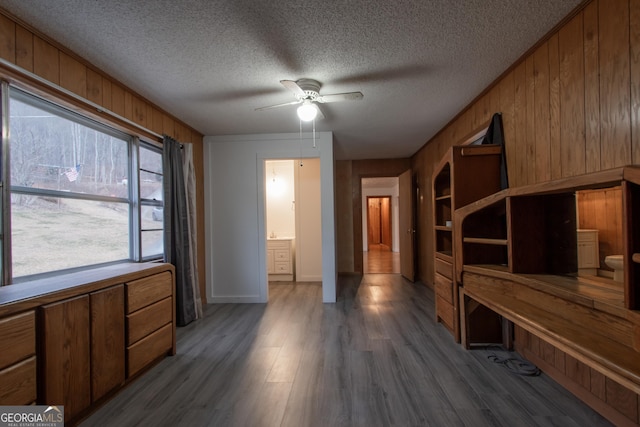 interior space with wood-type flooring, ceiling fan, a textured ceiling, and wooden walls