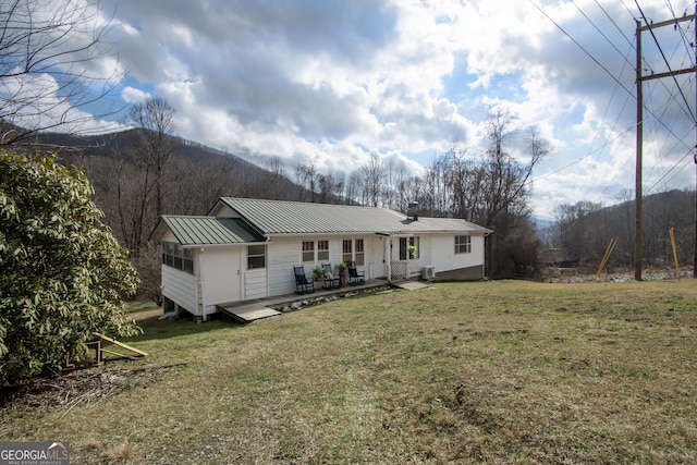 back of property featuring a yard and a deck with mountain view