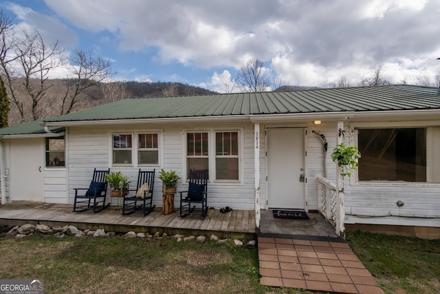 rear view of property featuring a wooden deck and a lawn