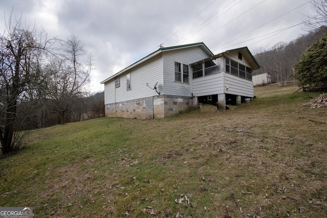 rear view of house featuring a sunroom and a lawn