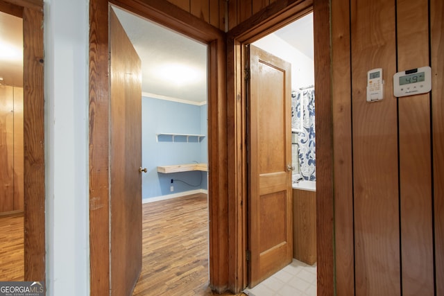 hallway with crown molding and light hardwood / wood-style flooring