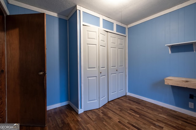 unfurnished bedroom with a closet, dark hardwood / wood-style floors, and a textured ceiling