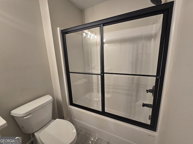 bathroom featuring toilet and combined bath / shower with glass door