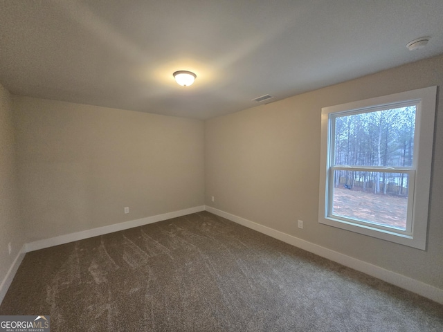 spare room featuring dark colored carpet