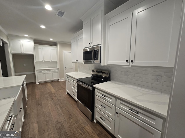 kitchen with white cabinetry, appliances with stainless steel finishes, dark wood-type flooring, and light stone counters