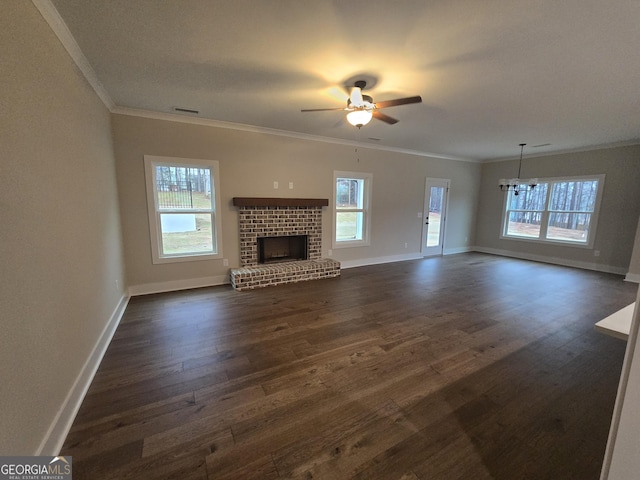 unfurnished living room with ornamental molding, dark wood-type flooring, ceiling fan with notable chandelier, and a fireplace