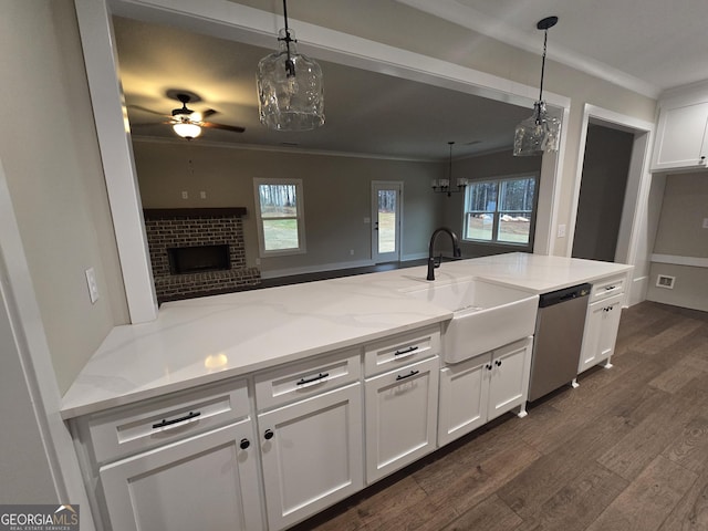 kitchen featuring decorative light fixtures, sink, white cabinets, stainless steel dishwasher, and light stone counters