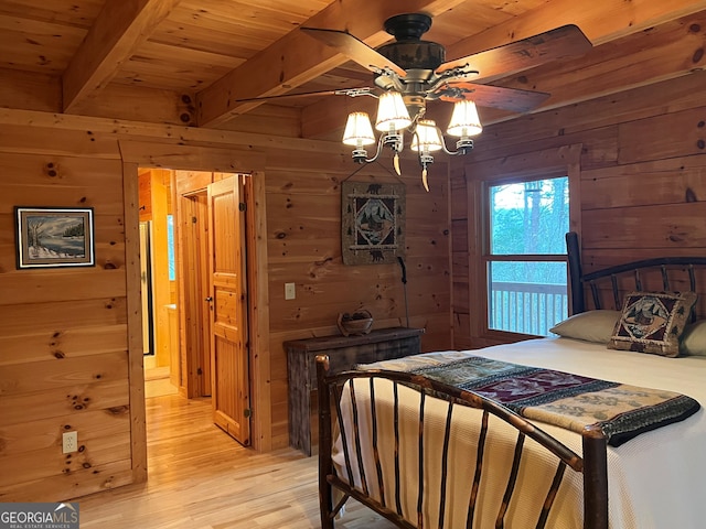 bedroom with beamed ceiling, wooden ceiling, wooden walls, and light wood-type flooring