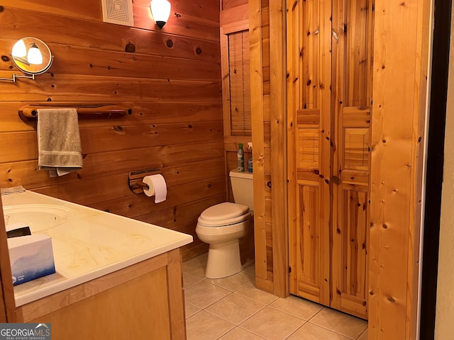 bathroom with toilet, vanity, wooden walls, and tile patterned flooring