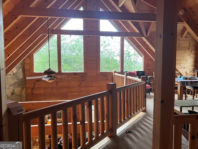 hallway with wooden walls, lofted ceiling with beams, and carpet flooring