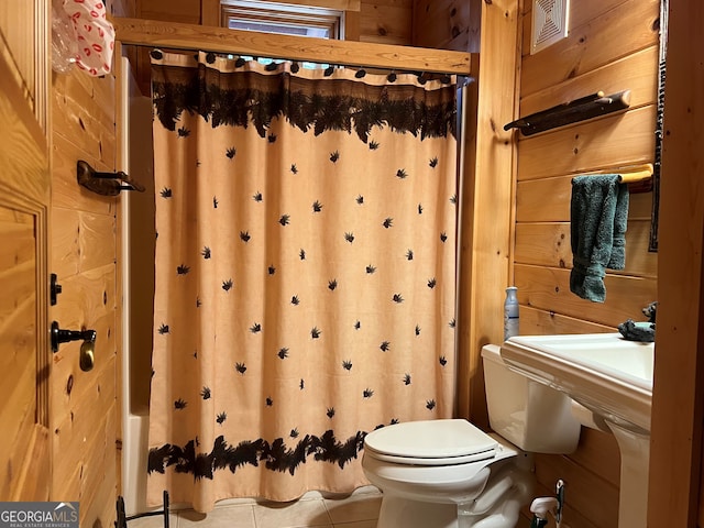 bathroom featuring tile patterned floors, toilet, and wood walls