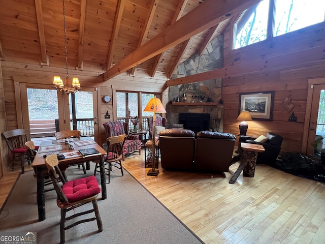 living room featuring a stone fireplace, wood ceiling, an inviting chandelier, wood-type flooring, and wooden walls